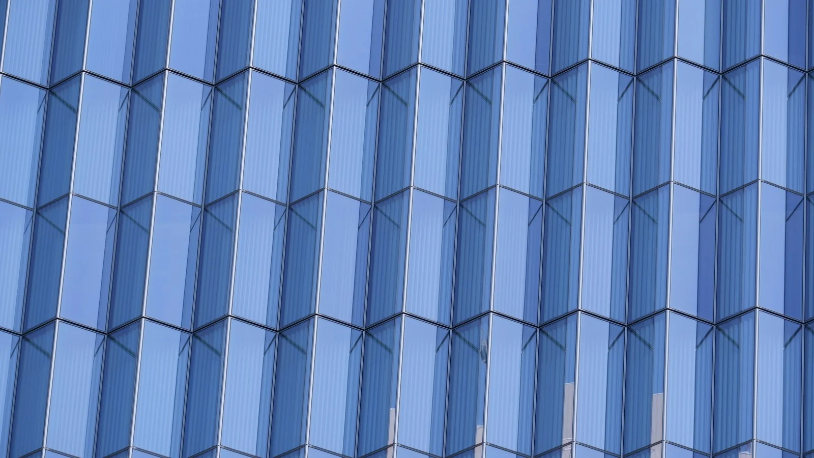 A geometric facade of folded blue glass
