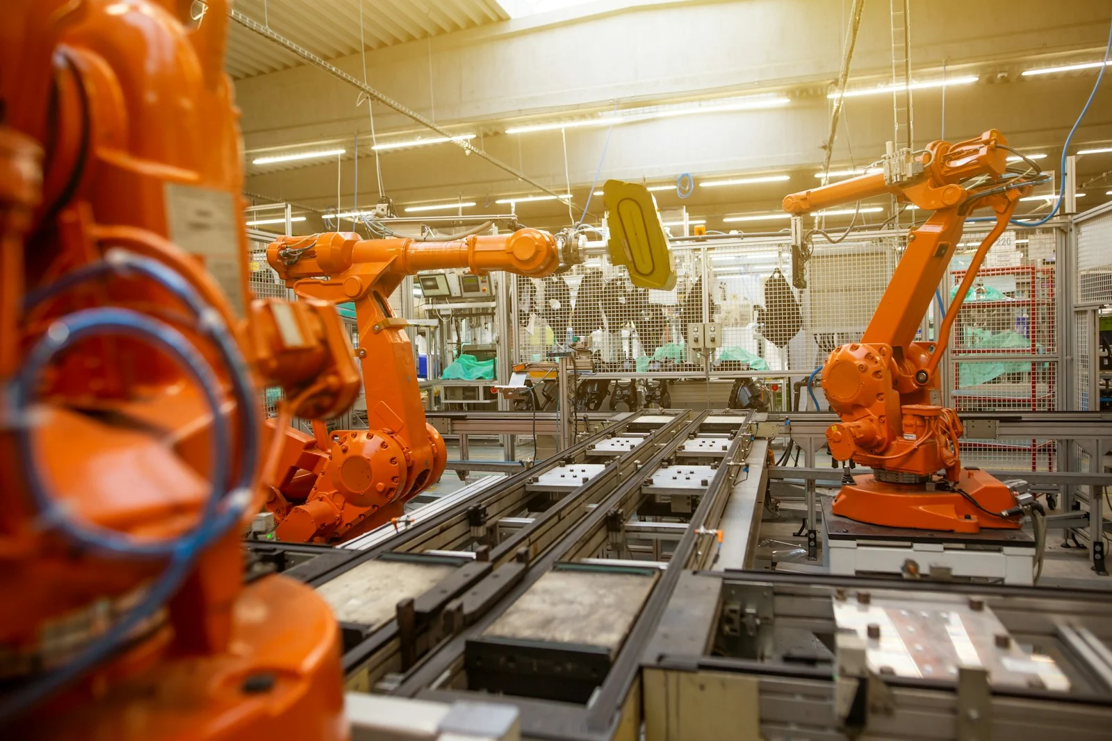 Orange industrial robotic arms arranged along an automotive assembly line
